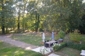 two umbrellas and a picnic table in a garden at Maison lAmrique welcome you to one of their rooms Dogs are also welcomed in Saint-Jean-le-Blanc