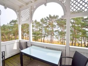 einen Tisch und Stühle auf einer Veranda mit Fenstern in der Unterkunft Strandvillen Binz - Ferienwohnung mit Meerblick, 2 Schlafzimmern und Balkon SV-012 in Binz