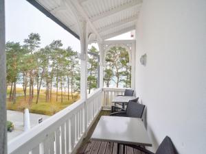 einen Balkon mit Tischen und Stühlen und Waldblick in der Unterkunft Strandvillen Binz - Ferienwohnung mit Meerblick, 2 Schlafzimmern und Balkon SV-012 in Binz