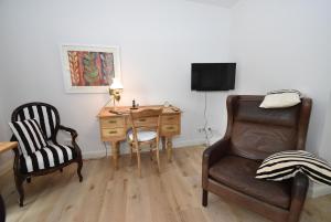 フレンスブルクにあるfewo1846 - Belvedere - behaglich ausgestattete Wohnung mit Balkon und Hafenblickのデスク、椅子、デスク、椅子が備わる客室です。