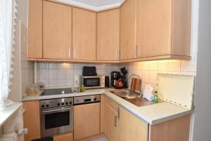 a kitchen with wooden cabinets and a sink and a microwave at fewo1846 - Belvedere - behaglich ausgestattete Wohnung mit Balkon und Hafenblick in Flensburg