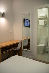 a room with a desk and a toilet and a desk and a computer at Alda Alborán Rooms in A Coruña