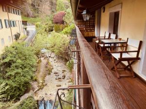 a balcony with tables and chairs and a river at La Casa al Torrente in Riva del Garda