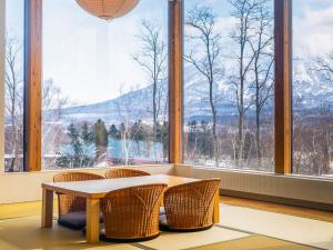a room with a table and chairs in front of a window at Aoyama Lodge in Niseko