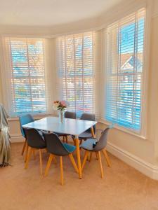 a dining room with a table and chairs and windows at Alexandra Beach Haven in Worthing