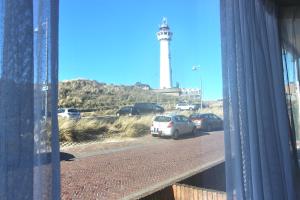- une vue sur un phare depuis une fenêtre avec des voitures dans l'établissement Torenlicht, à Egmond aan Zee