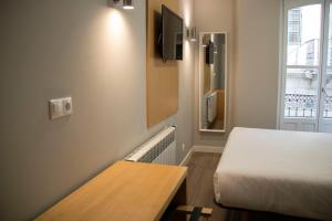 a room with a bed and a table and a window at Alda Alborán Rooms in A Coruña
