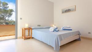 ein weißes Schlafzimmer mit einem Bett mit blauen Laken und einem Fenster in der Unterkunft VISTA ALEGRE in Tamariu + 16 Fotos
