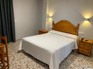 a bedroom with a white bed with a wooden headboard at Hotel Estrella Del Mar in Motril