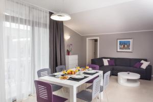 sala de estar con mesa blanca y sillas moradas en Apartments ZoomZoom en Dubrovnik