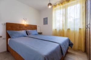 a bedroom with a bed with a blue blanket and a window at Apartment Magic Garden in Baška