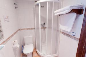 a white bathroom with a shower and a toilet at Hotel Costa de Rodiles in Selorio +22 photos