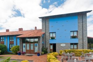 a blue building with a patio and tables at Hotel Costa de Rodiles in Selorio