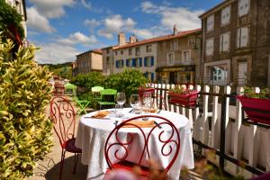 a table with chairs and wine glasses on a balcony at Hôtel Restaurant La Terrasse in Saugues