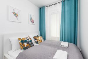 a bedroom with a bed with blue curtains and a window at Apartamenty Osiedle Bursztynowe II by Renters in Kołobrzeg