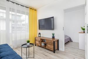 a living room with a couch and a tv on a wall at Apartamenty Osiedle Bursztynowe II by Renters in Kołobrzeg