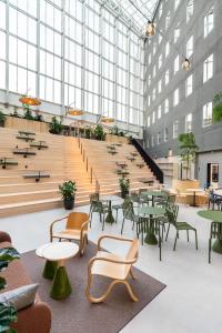 VALO Hotel & Work Helsinki في هلسنكي: غرفة كبيرة بها طاولات وكراسي ودرج