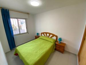a bedroom with a green bed and a window at Apartamentos Irta Playa Altamar in Alcossebre