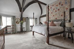Luxury Cotswolds Cottage optional Hot Tub, Castle Combe في كاسل كومب: غرفة نوم مع سرير المظلة ومكتب
