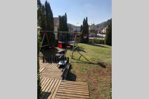 una terraza de madera con un parque infantil en un patio en Logement au calme dans une maison., en Moirans-en-Montagne