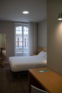 um quarto de hotel com uma cama e uma janela em Alda Alborán Rooms em La Coruña