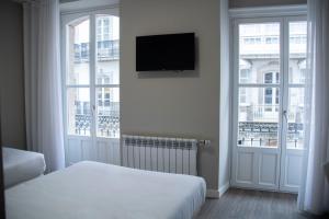 a bedroom with two beds and a flat screen tv at Alda Alborán Rooms in A Coruña