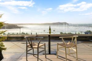 a table and two chairs and a table with a bottle of wine at Polzeath Beach House in Polzeath
