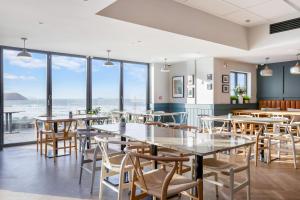 a restaurant with tables and chairs and large windows at Polzeath Beach House in Polzeath