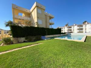 a building with a swimming pool in front of a yard at Apartamentos Playa Del Moro III Altamar in Alcossebre