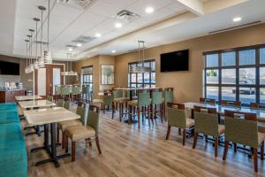 a restaurant with tables and chairs and a flat screen tv at Comfort Inn & Suites in Harrisonburg