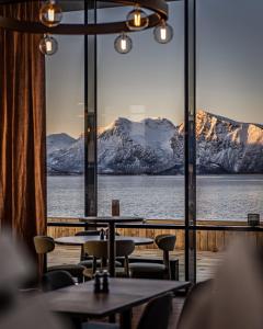 un restaurante con mesas y vistas a las montañas cubiertas de nieve en Scandic Sortland, en Sortland