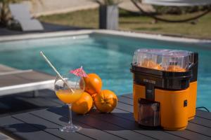 リル・シュル・ラ・ソルギュにあるIn Elsama piscine chaufféeのプールサイドのテーブルの上でドリンクとオレンジを楽しめます。