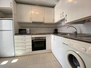 - une cuisine avec des placards blancs et un lave-linge/sèche-linge dans l'établissement Apartamentos Jardines del Puerto Altamar, à Alcossebre