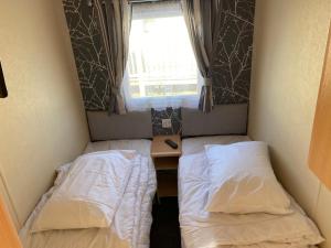 a small room with two beds and a window at 4 bedroom 10 berth caravans with Hot Tub ,Mountain Bikes Tattershall Lakes in Tattershall