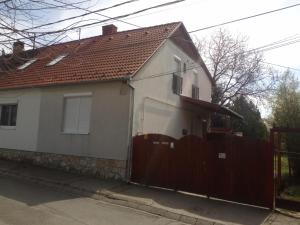una casa blanca con una puerta y una valla en Budai Vám Apartmanház en Pécs