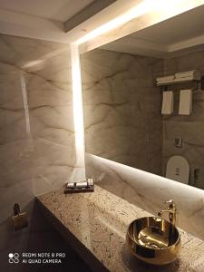 Hotel Poonja International في منغالور: حمام مع حوض ومرآة