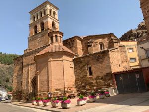 an old brick building with a clock tower and potted plants at Casa Rural Arenal in Torrijo de la Cañada