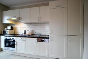 eine weiße Küche mit weißen Schränken und Geräten in der Unterkunft Villa Seeluft by Rujana in Ostseebad Sellin