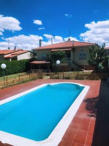 a blue swimming pool in front of a house at Chalet piscina privada Salamanca in Calvarrasa de Abajo