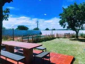 een picknicktafel met banken en uitzicht op het water bij Chalet piscina privada Salamanca in Calvarrasa de Abajo