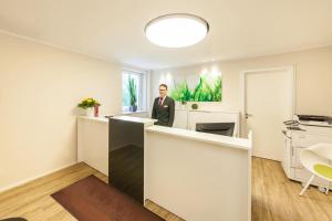 a man in a suit standing at a counter in a room at acora Fürth Living the City- Apartments in Fürth