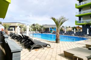 a pool with a bunch of chairs next to a building at Glamour Sea view Family Apartments - Spa n Pools Resort in Mamaia