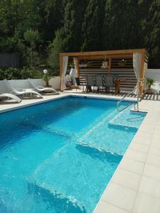 une grande piscine bleue avec des chaises et un kiosque dans l'établissement Apartamento Milka Gandia Marchuquera, à Gandía