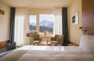 a bedroom with a bed and two chairs and a window at signinahotel in Laax
