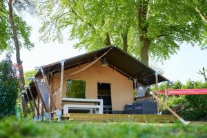 a house with a pitched roof and a porch at Glamping Betuwe in Kesteren +25 photos
