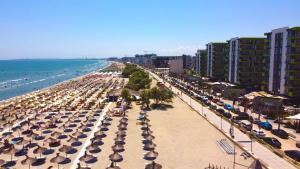 a beach with umbrellas and chairs and the ocean at Glamour Sea view Family Apartments - Spa n Pools Resort in Mamaia
