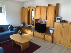 sala de estar con armarios de madera, TV y mesa en Haus Lucia Appartment "Schönblick" en Schönwald