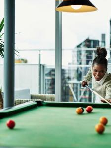 Dziewczyna grająca w bilard z kijem na stole bilardowym w obiekcie Chic Studios and Apartments at Chapter South Bank in London w Londynie