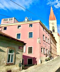 a pink building with a clock tower on a street at Boutique Apartments U Rolanda in Znojmo