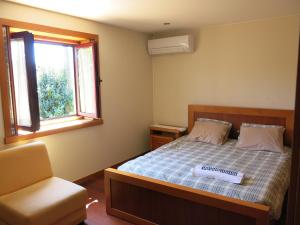 a bedroom with a bed and a chair and a window at Casa Dos Tinocos in Braga